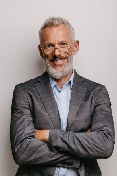 Confident mature businessman in formalwear keeping arms crossed and smiling against white background